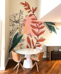 a white table and chairs in front of a floral wall mural