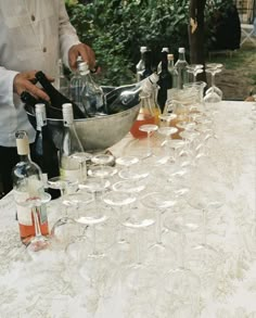 several wine glasses and bottles are lined up on a table with a man pouring them