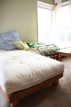 a bed sitting in the middle of a living room next to a window with curtains