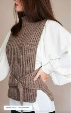 a woman in black pants and a white shirt is wearing a brown sweater with sleeves