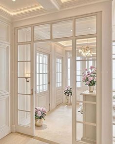 the interior of a house with white walls and doors, flowers in vases on the table