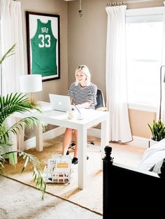 a woman sitting at a desk in front of a laptop computer on top of a white table