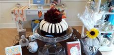 a table topped with a cake covered in icing next to wine glasses and cards