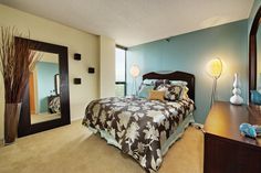 a bed room with a neatly made bed and a large mirror on the wall above it