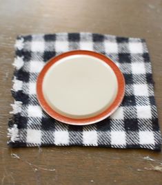 an empty plate sitting on top of a black and white checkered placemat with a red rim