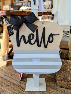 a wooden sign that says hello hanging on a clothes hanger in a clothing store