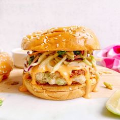 a chicken sandwich with cole slaw and mayonnaise on a wooden cutting board