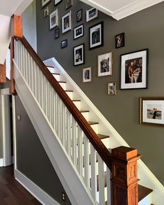 a staircase with pictures on the wall and framed photos on the wall above it, along with a wooden banister