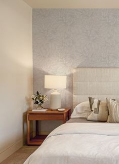 a white bed sitting next to a night stand with two lamps on top of it