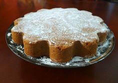 a cake sitting on top of a wooden table covered in powdered sugar and icing