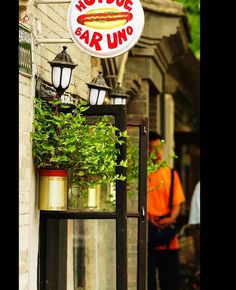 there is a sign that says outside bar uno on the side of a building with potted plants