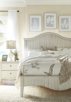 a white bed sitting in a bedroom next to two pictures on the wall above it