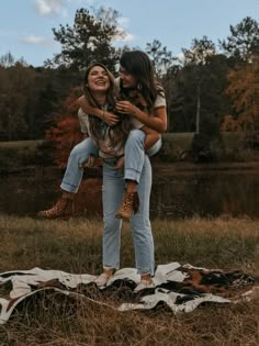 two women are hugging in the middle of a field