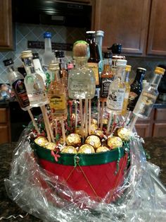 a basket filled with lots of liquor bottles on top of a kitchen counter covered in plastic