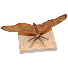 a bronze sculpture of a dragonfly on a marble base with two wings spread out