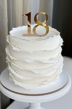 there is a white cake with gold numbers on the top and bottom tiers that are stacked together