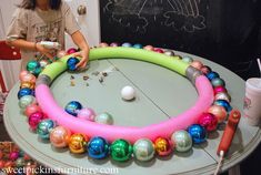 a woman standing in front of a cake decorated with balls