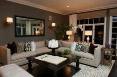 a living room with couches, tables and lamps on the floor in front of windows