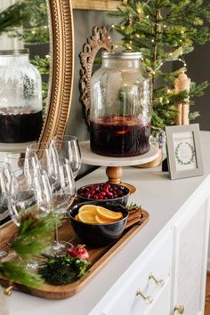 a table topped with wine glasses filled with liquid and orange slices next to a mirror