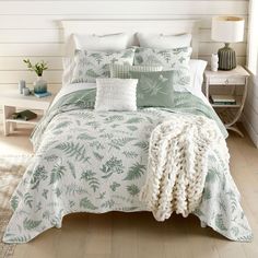 a bed with green and white comforters in a bedroom