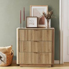 a wooden dresser sitting next to a wall with pictures on top of it and candles in front of it