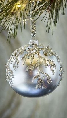 a silver ornament hanging from a christmas tree