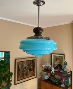 a blue light hanging from the ceiling in a living room with pictures on the wall