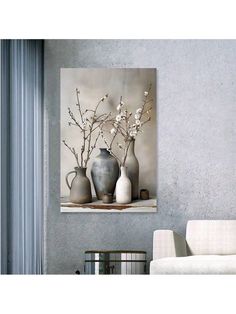 three vases with white flowers in them on a table next to a chair and wall