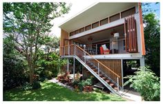 a house that is in the middle of some trees and grass with stairs going up to it