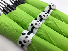 four panda bears are sitting on green napkins with black and white forks in front of them