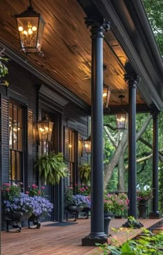 the porch is lined with potted plants and hanging lights on the side of the house