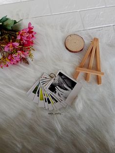 a bunch of pictures sitting on top of a white fur covered floor next to a wooden easel