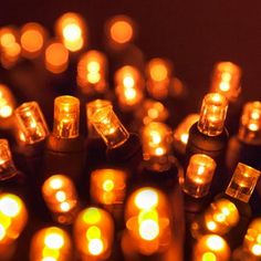 many lit candles sitting on top of each other in front of a dark background with lots of small ones