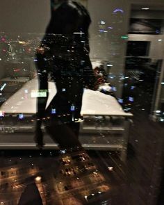 a woman standing on top of a roof in front of a cityscape at night