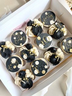 a box filled with cupcakes covered in black and white frosting sitting on top of a table