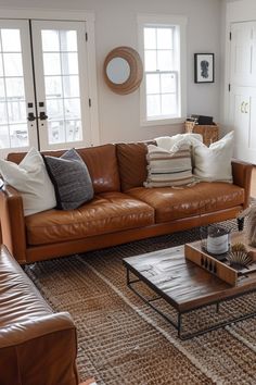 a living room with brown leather furniture and pillows on the couches, coffee table