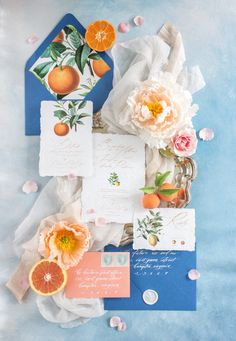 an assortment of stationery items including oranges, flowers and napkins on a blue background