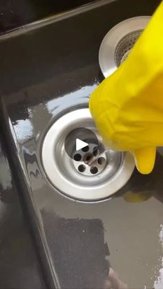 a person in yellow gloves is washing a sink