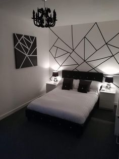 a black and white bedroom with a bed, chandelier and two nightstands