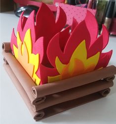 an origami fire place setting on top of rolled up paper