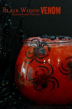 an orange vase with black decorations on it and some plants in the background, along with text that reads black widow venom halloween punch