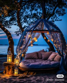 a canopy bed with lights hanging from it's sides on the beach at night