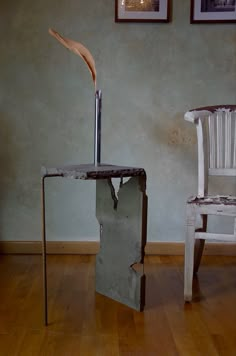 two chairs and a table in a room with wood flooring, one chair has a metal pole sticking out of it