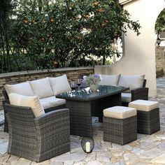 an outdoor table and chairs set up on a stone patio with orange trees in the background