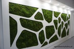 a wall covered in green moss with lights on the top and below it is a white panel