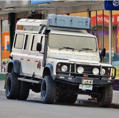 a white land rover is parked on the side of the road in front of a store