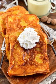 pancakes with whipped cream and nuts on a wooden plate