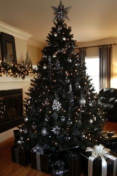 a black christmas tree with silver and white ornaments is in the middle of a living room