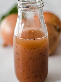 a glass jar filled with liquid sitting on top of a white table next to oranges