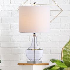 a table lamp sitting on top of a white dresser next to a potted plant